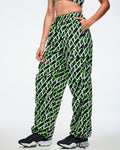 Female model wearing black cargo pants with an allover black, white and green “Z” crisscross pattern, left hand in her pocket, paired with black-and-white shoes.