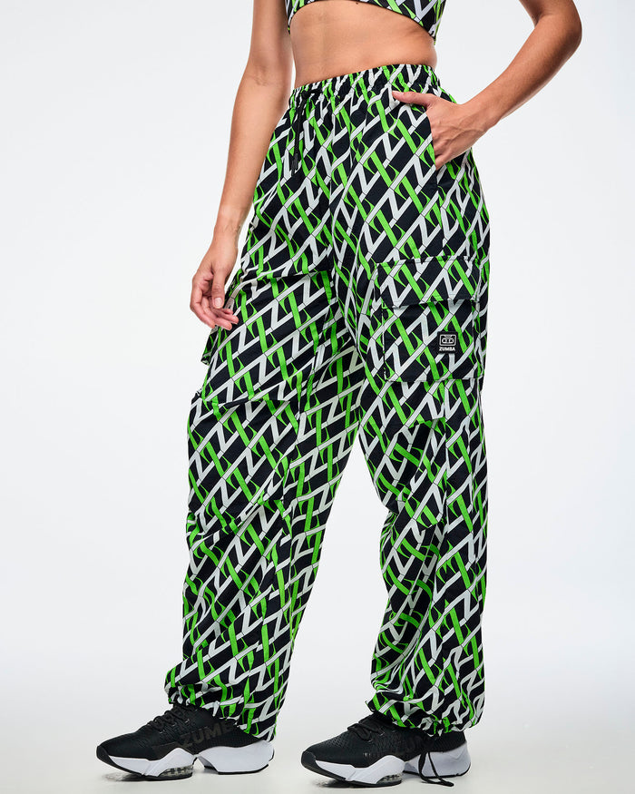 Female model wearing black cargo pants with an allover black, white and green “Z” crisscross pattern, left hand in her pocket, paired with black-and-white shoes.
