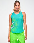 Female model wearing an aqua mesh racerback tank with a green-to-yellow gradient dot design, with a white Zumbito on the lower right and paired with green pants.