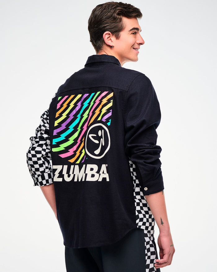 Shown from the back, male model wearing a black flannel button-up with a checkered sleeve and a rainbow lightning bolt "ZUMBA" graphic on the back.