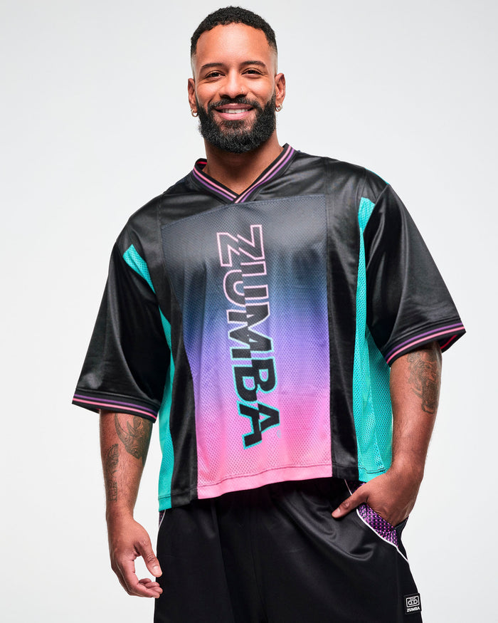 Close-up of a male model wearing an oversized black jersey tee with an aqua side panel and pink-to-purple gradient "ZUMBA" print.
