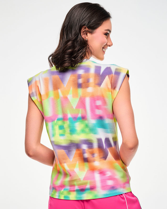 Shown from the back, female model wearing a multi-color extended shoulder tank with a blurred wordmark print.