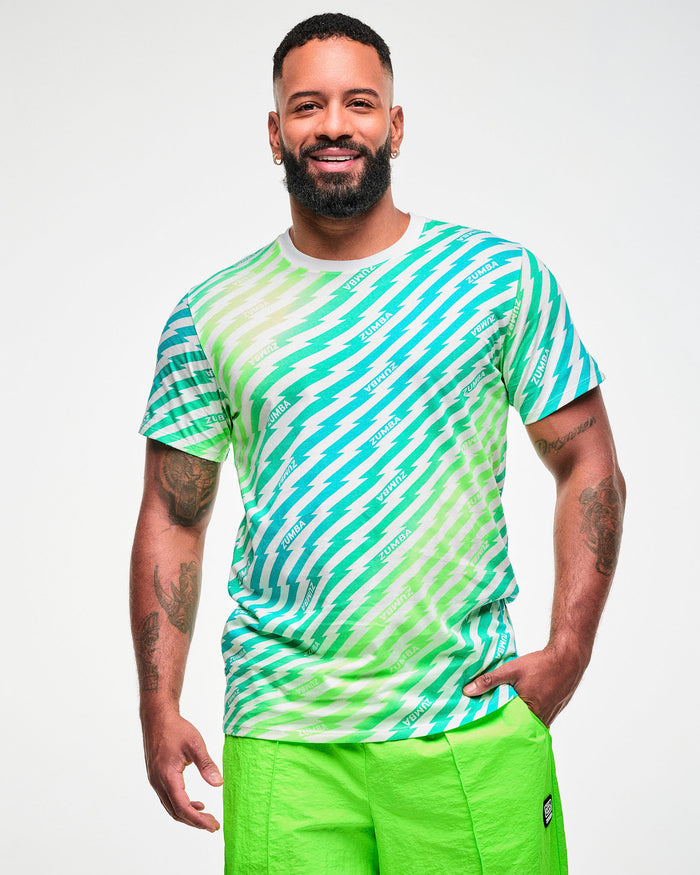 Male model wearing a green and aqua lightning bolt-striped tee with "ZUMBA" text, paired with lime green shorts.