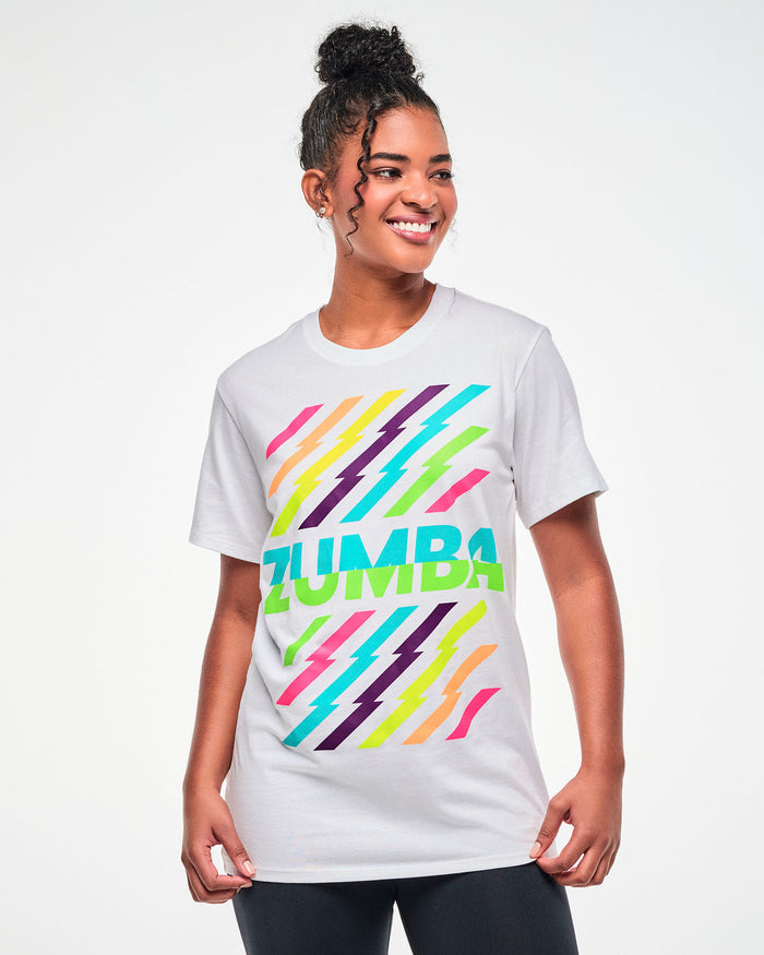 Female model wearing a white tee with a colorful lightning bolt-striped print, and aqua and green "ZUMBA" text in the middle.