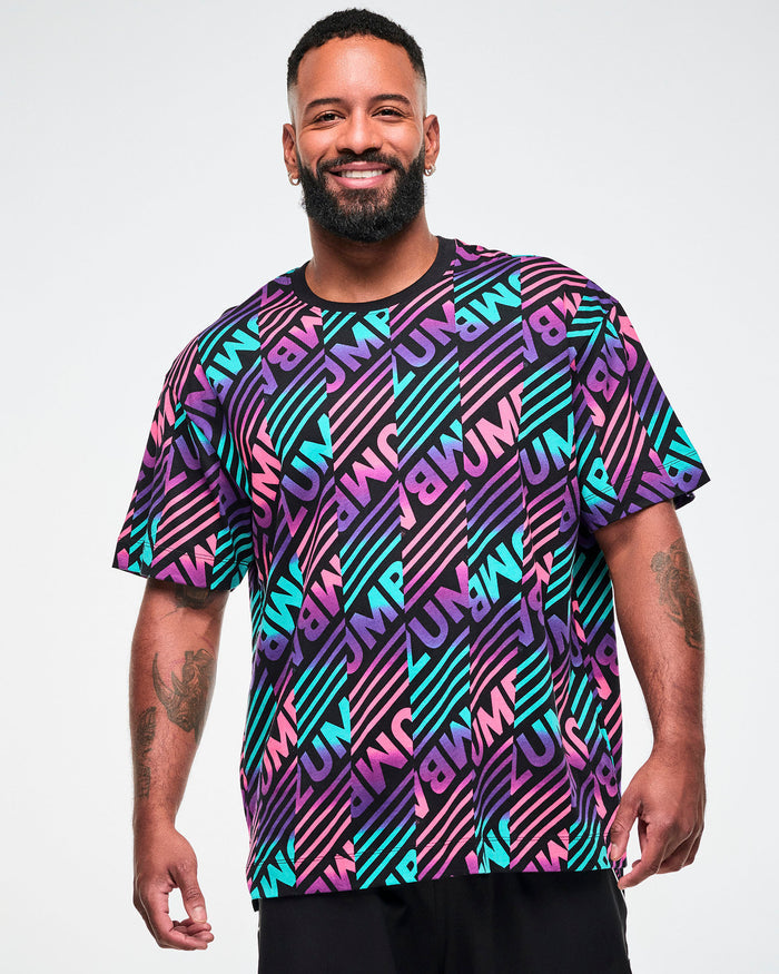 Male model wearing a black tee with a colorful pink, aqua, and purple diagonal striped "ZUMBA" broken-pattern print.