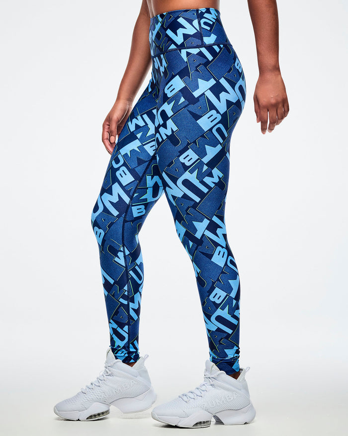 Side view of a female model wearing blue patterned leggings with white sneakers on a light gray background.