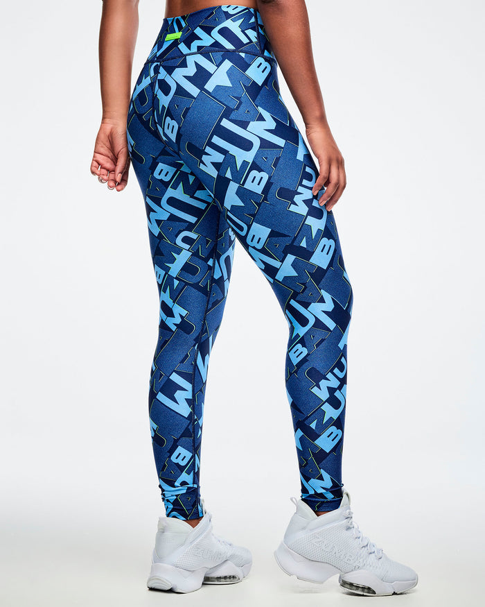 Back view of female model wearing blue patterned leggings with white sneakers on a light gray background.