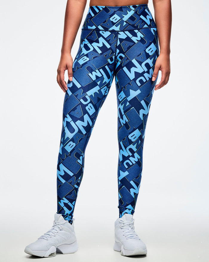Front view of a female model wearing blue patterned leggings with white sneakers on a light gray background.