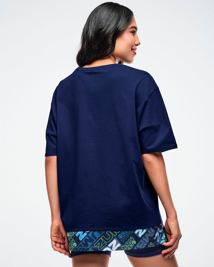 Back view of a female model wearing a blue "Zumba" shirt.