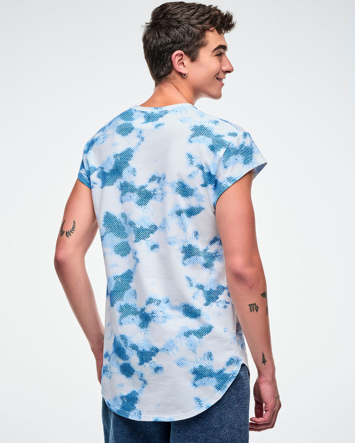 Back view of male model wearing a Zumba Dance Co t-shirt with a blue and white pattern on a plain background.