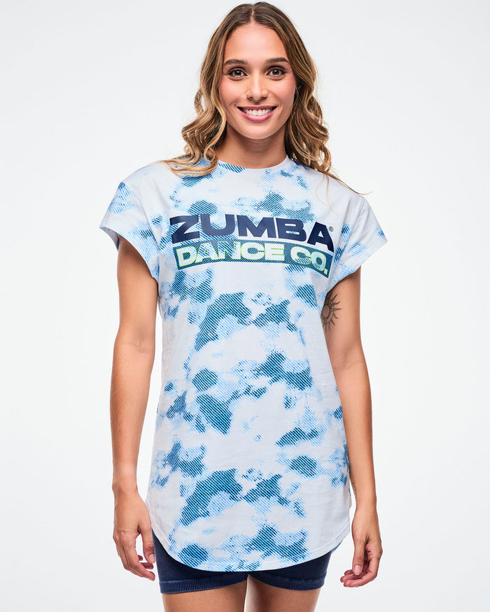 Female model wearing a Zumba Dance Co t-shirt with a blue and white pattern on a plain background.