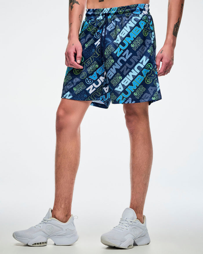 Male model wearing blue patterned shorts with 'Zumba' branding on a white background.