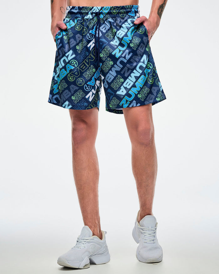 Front view of a male model wearing blue patterned shorts with both hands in his pockets and paired with white shoes.