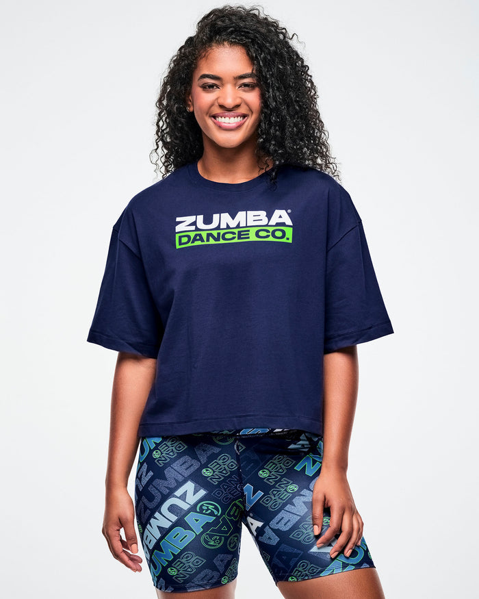 Female model wearing an indigo Zumba crop top with matching blue patterned shorts on a white background.
