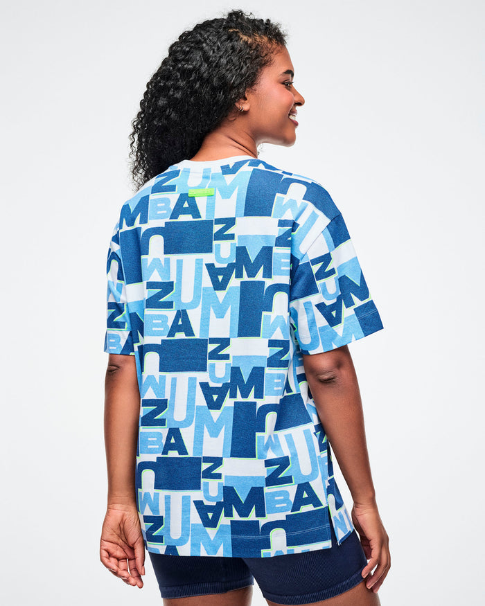 Back view of female model wearing a blue patterned top with a plain background.