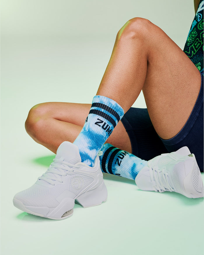 Female model wearing blue and white tie-dye socks with dark blue stripes paired with white sneakers.