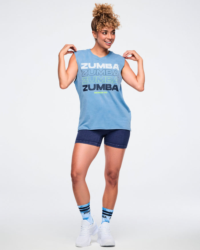 Female model wearing a Zumba branded outfit and paired with blue and white socks and white sneakers.