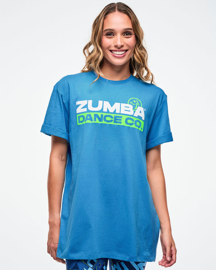 Female model wearing a light blue Zumba t-shirt on a white background.