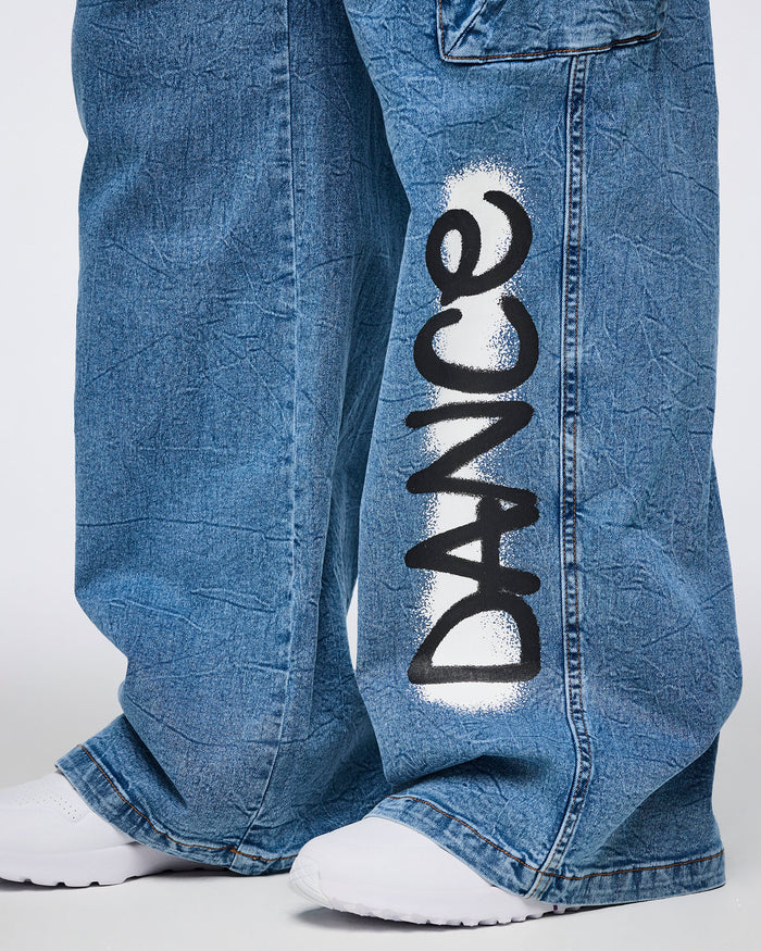Female model wearing denim cargo pants with a close-up of the 'DANCE' spray-painted on the leg against a white background.
