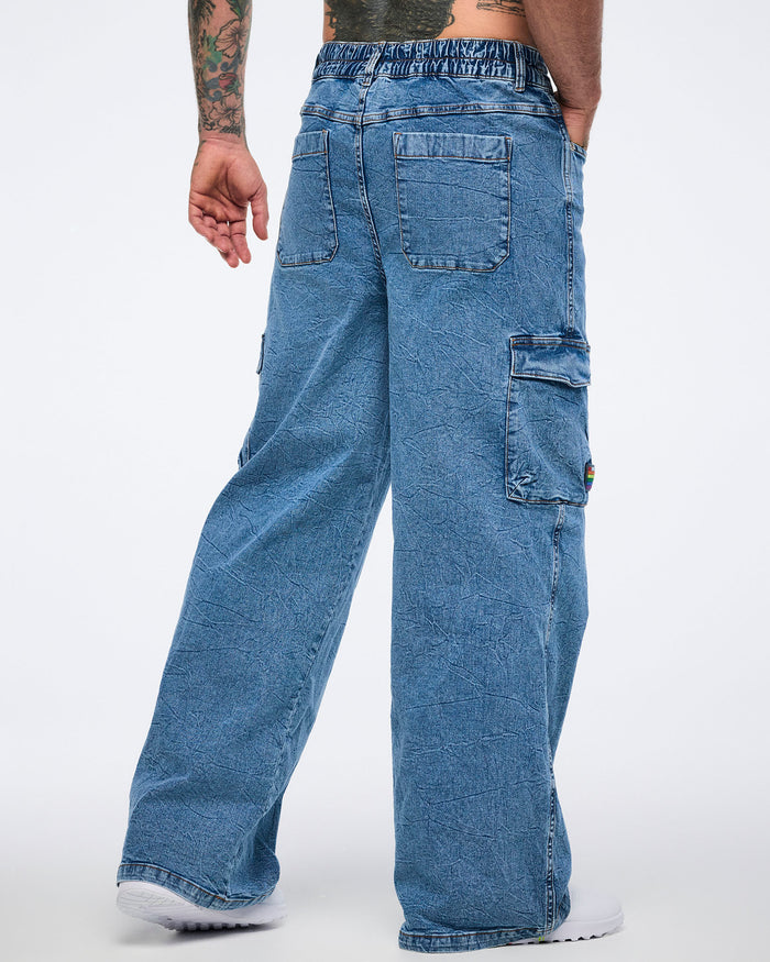 Male model back view in wide‑leg denim cargo pants with cargo pockets against a white background.