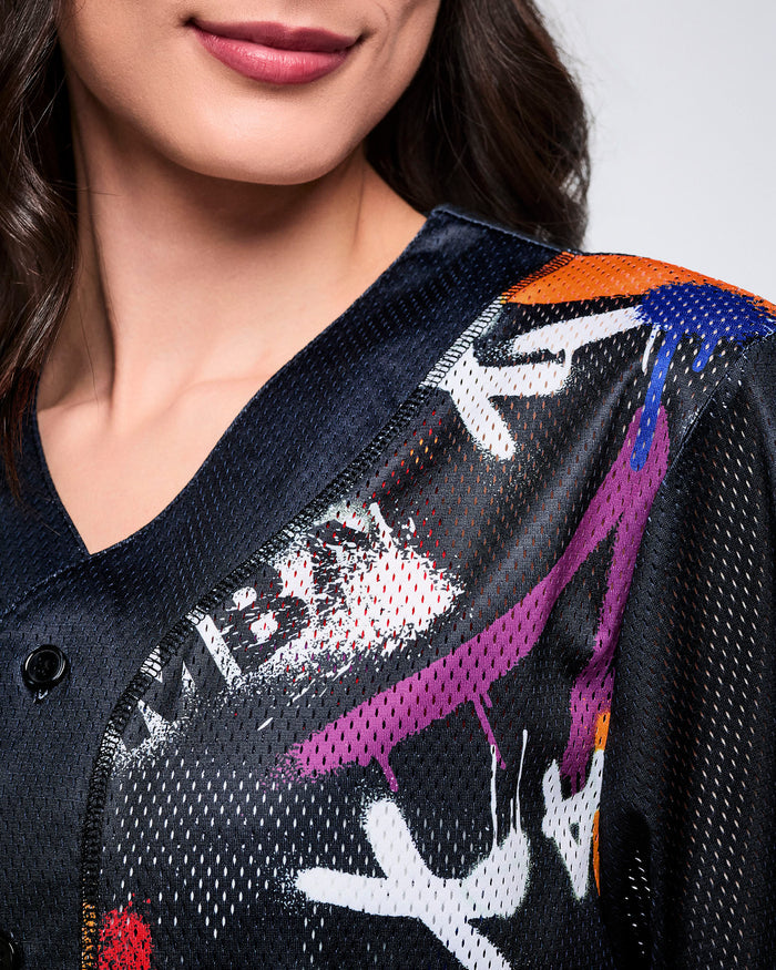 Close up detail of a female model wearing a black mesh Zumba jersey with bold multicolor graphics on a white background.