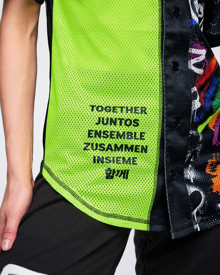 Close-up of a female model in a neon green and black Zumba jersey featuring 'TOGETHER, JUNTOS, ENSEMBLE, ZUSAMMEN, INSIEME and Korean text' on white background