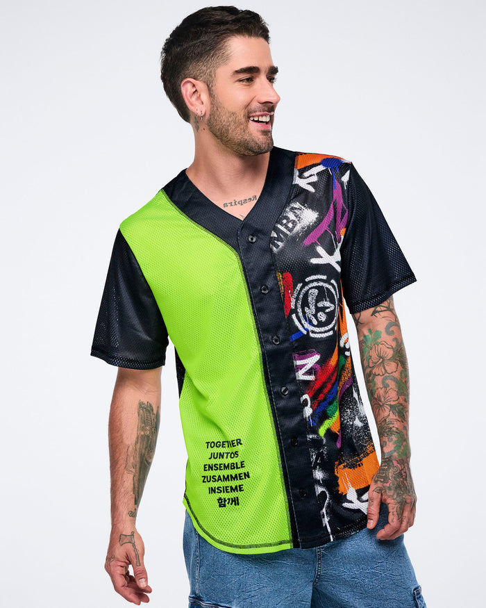 Male model in neon‑green and black graphic jersey with denim cargo pants against a white background.