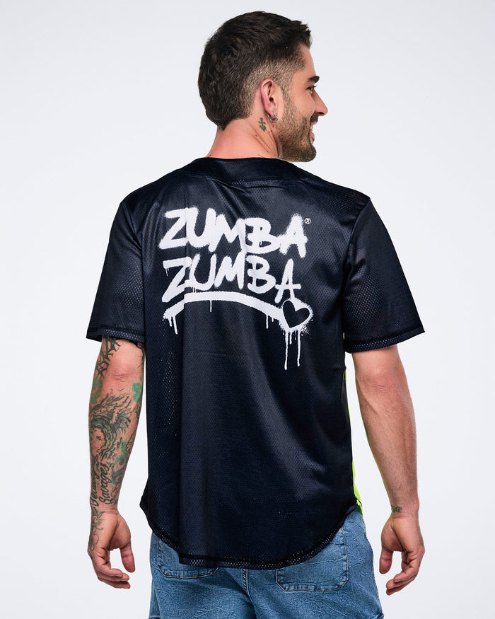 Male model showing the back of a black graphic Zumba jersey and denim cargo pants against a white background.