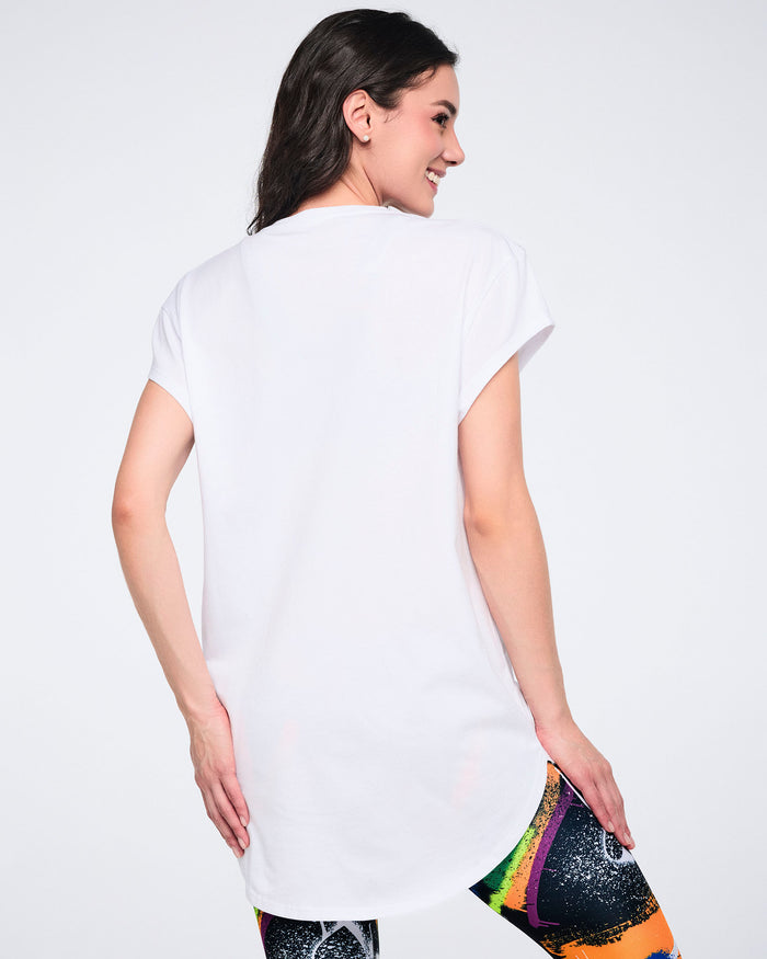 Back view of a female model wearing a white t-shirt with colorful leggings, on a white background.