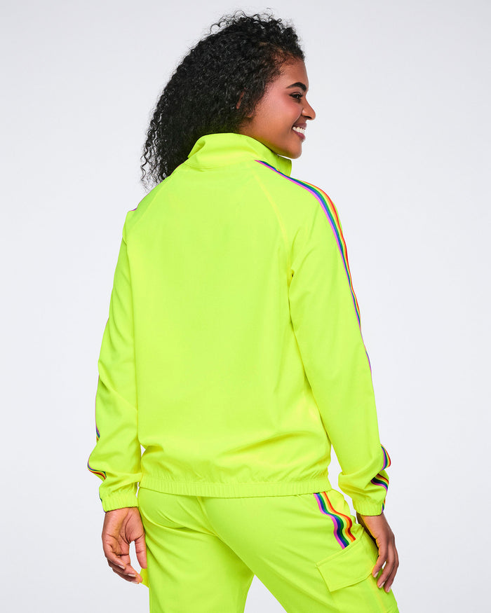 Back view of a female model wearing a bright yellow tracksuit with rainbow stripes on a white background.