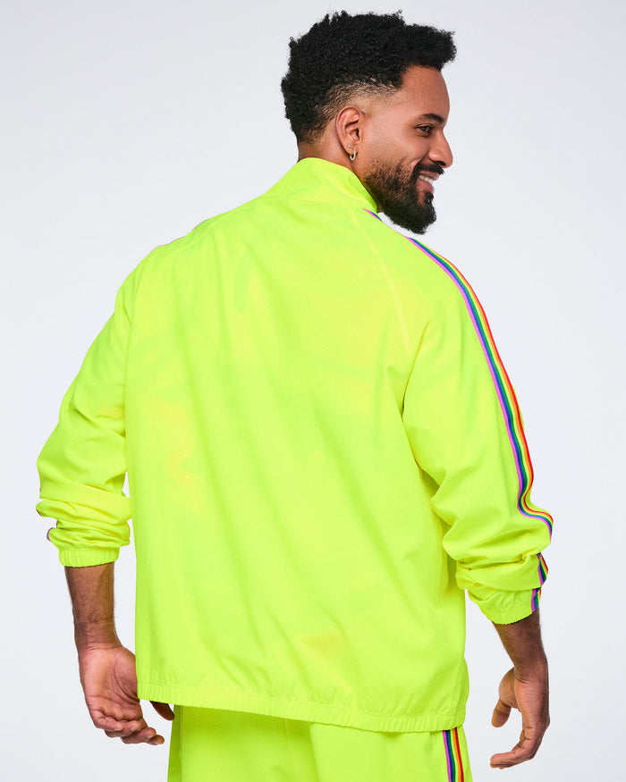 Back view of a male model wearing a bright yellow jacket and matching pants with rainbow stripes on a white background.