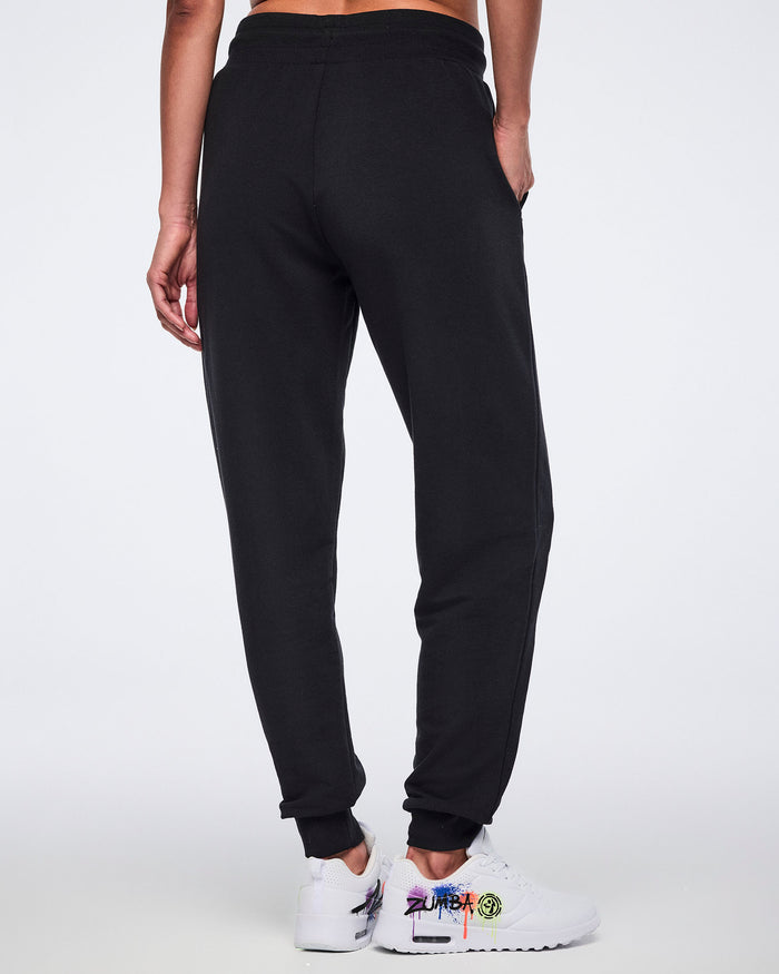 Female model wearing black sweatpants shown from the back, on a white background.