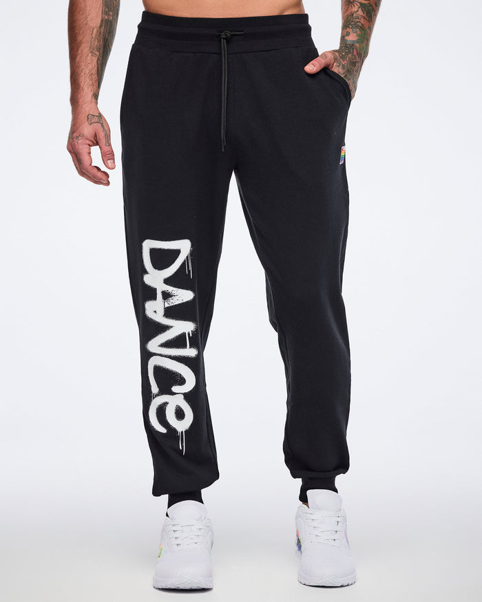 Black sweatpants worn by a male model with 'DANCE' printed on the right leg, all shown on a white background.