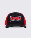 A black trucker-style hat with red mesh side panels and a red embroidered ZUMBA logo outlined in silver studs on the front.