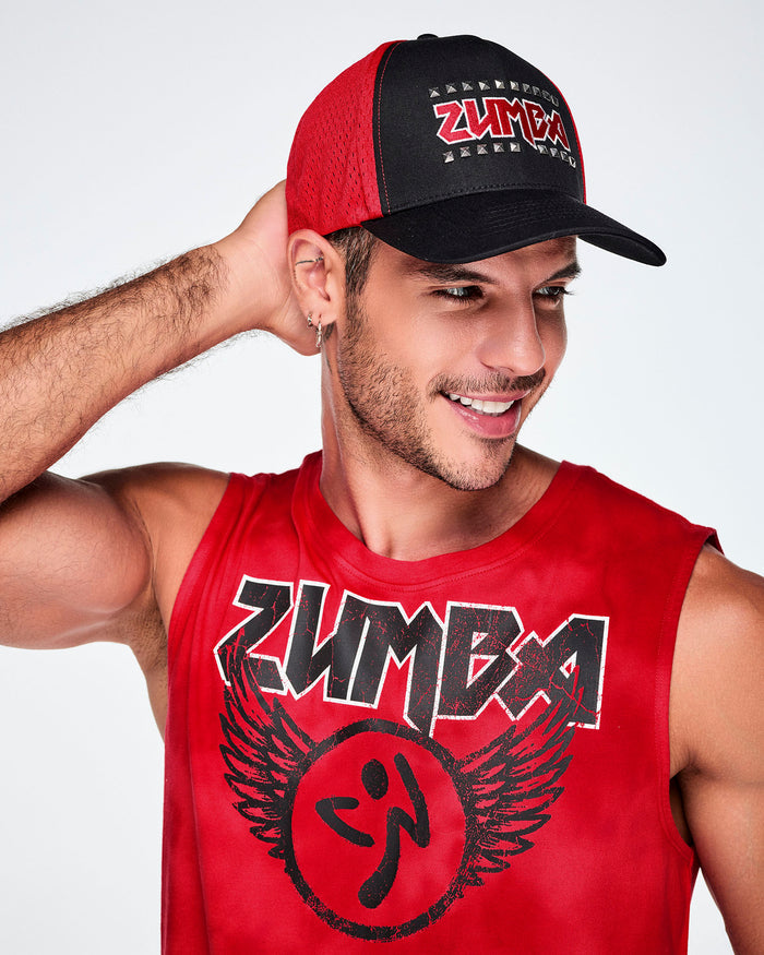 A male model wearing a black and red hat with ZUMBA in red, outlined in silver studs and paired with a red Zumba rock logo tank.