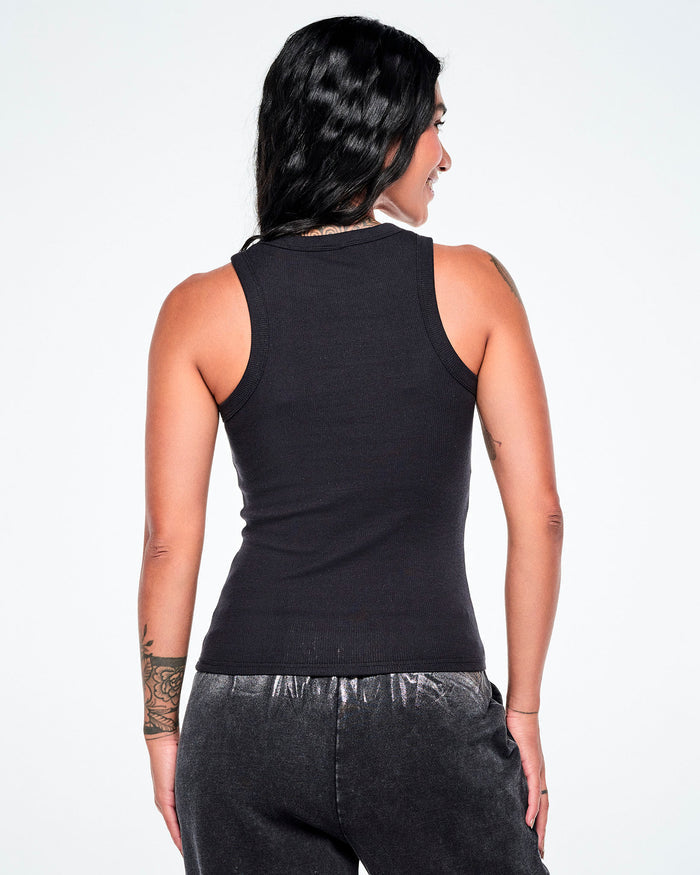 A woman shown from the back wearing a black sleeveless ribbed tank top and dark pants against a plain white background.