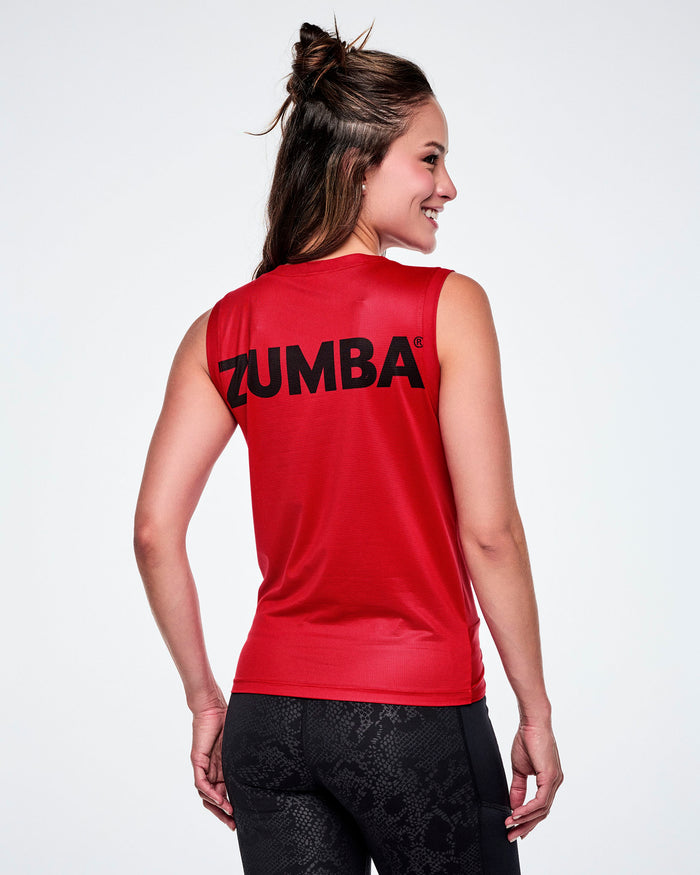 A female model shown from the back, wearing a red sleeveless athletic top with the brand name 'ZUMBA' printed in black across the upper back, paired with black leggings.