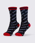 A pair of tube socks with a black base, white 'ZUMBA' text pattern, red cuffs, and red heels and toes against a white background.
