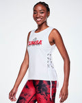 A female model wearing a white sleeveless tank top with a red ZUMBA text and overlayed with a small black Zumbito on top and on the bottom, black cursive text saying "DANCE THIS WAY and showing the side lace-up details and all paired with red and black leggings.