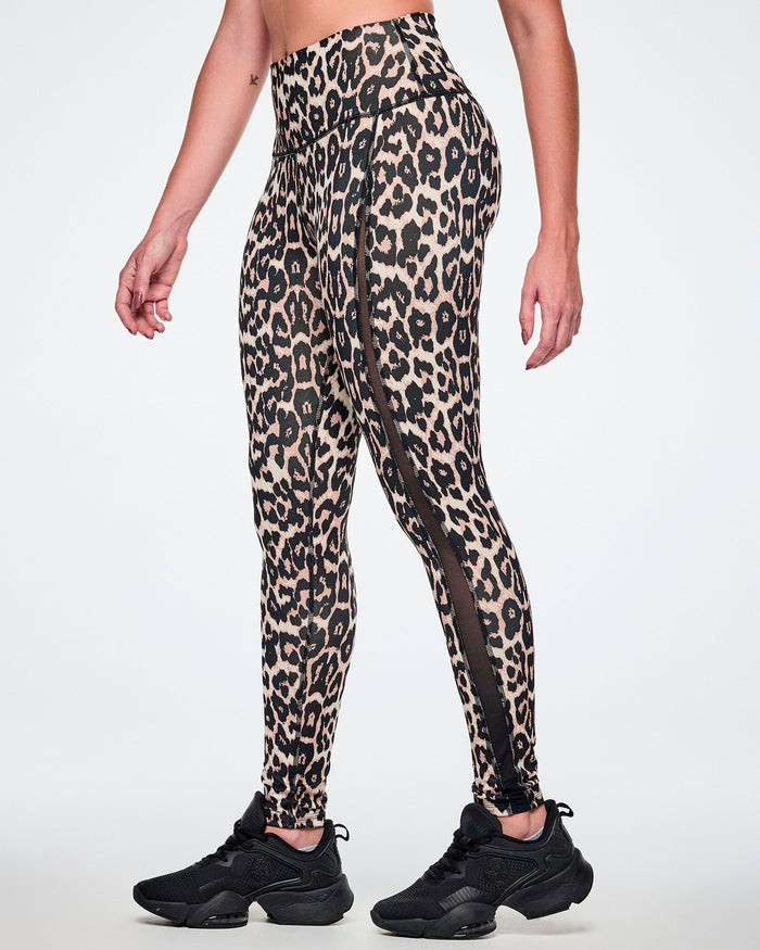 A female model wearing high-waisted leopard print leggings with sheer side panels, paired with black shoes.