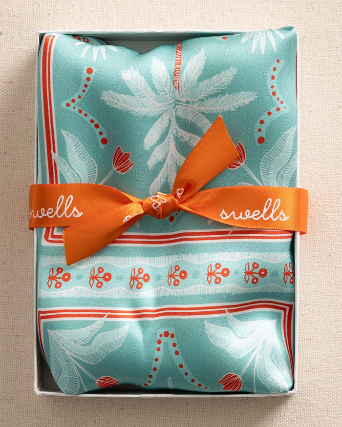 The front packaging view of the Southern Tide Swells Illustrated Palms Scarf by Southern Tide - Teal