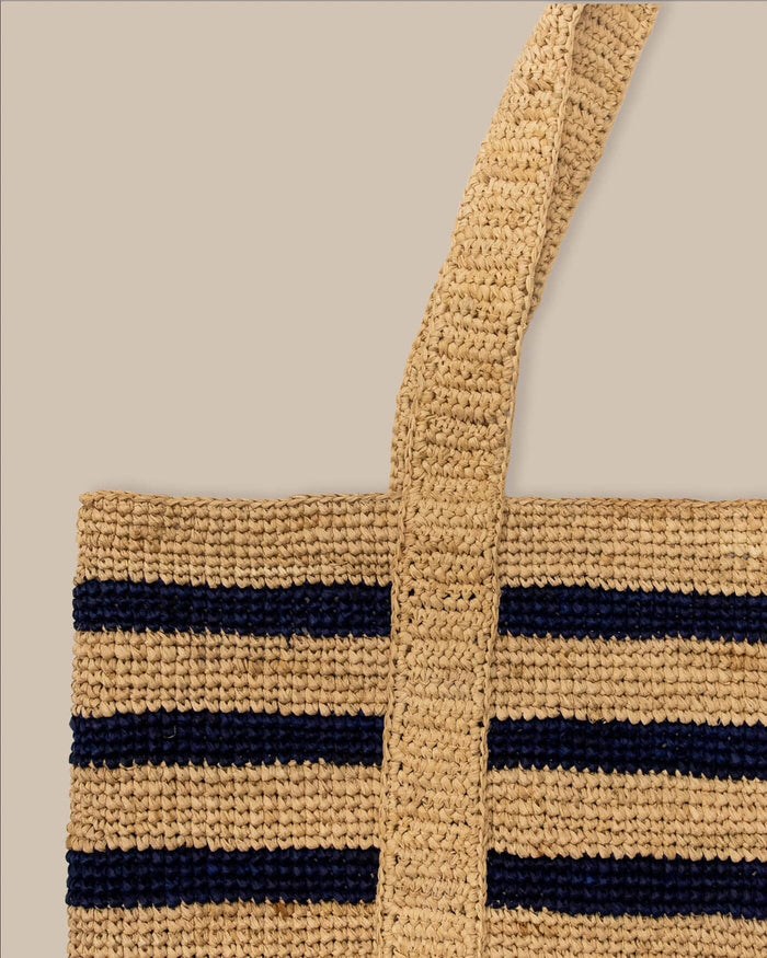 The front view of the Southern Tide Striped Straw Hat Carrier Beach Tote by Southern Tide - Navy