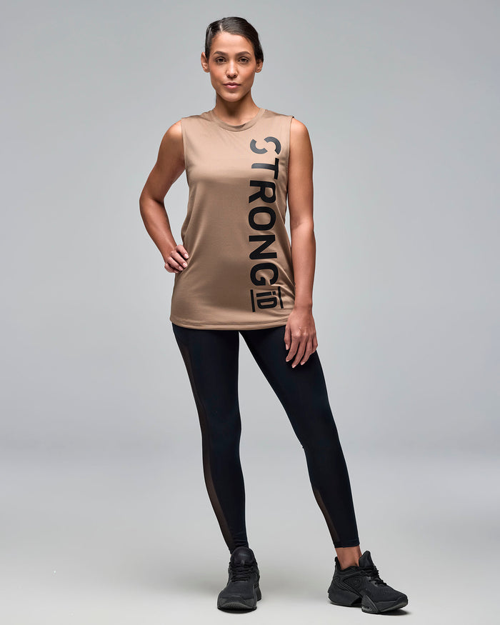 Taupe sleeveless athletic tank with a crew neckline and oversized vertical black "STRONG iD" logo, shown full length on a female model wearing black leggings and black sneakers.