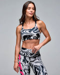 Black, white, and gray marble-print sports bra with a square neckline and black shoulder straps, shown on a female model wearing matching high-waisted leggings with bold pink "STRONG" lettering against a light gray studio background.