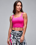 Bright pink cropped athletic tank with a square neckline and wide shoulder straps, shown on a female model wearing black, white, and gray marble-print leggings with pink accents against a light gray studio background.
