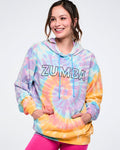 Female model wearing a tie-dye Zumba hoodie with a black outlined Zumba on the chest against a white background.