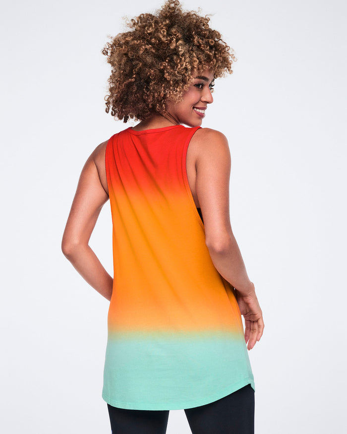 Female model wearing a sleeveless longline tank shown from the back in a red-to-orange-to-mint gradient, layered over black leggings.