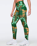Female model wearing high-waisted full-length leggings in a green, mint, orange, and black abstract print with a smooth fitted silhouette and white high-top sneakers.