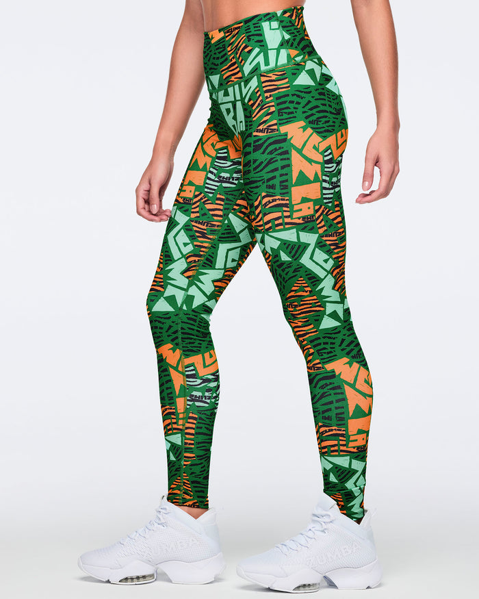 Female model wearing high-waisted full-length leggings in a green, mint, orange, and black abstract print with a smooth fitted silhouette and white high-top sneakers.