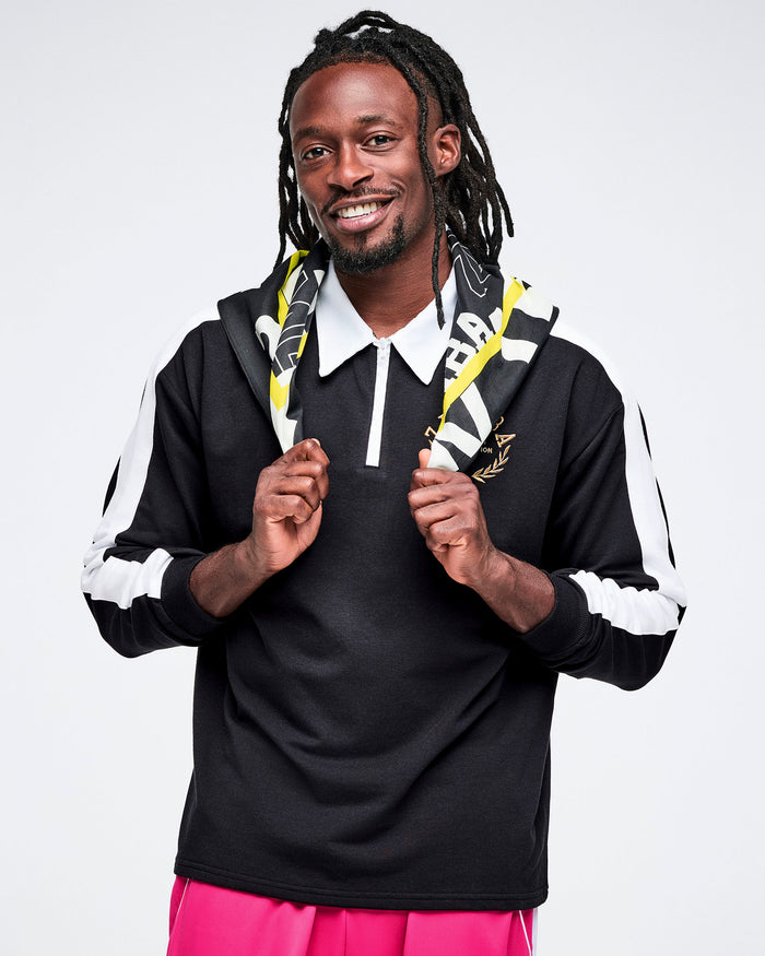 Male model wearing a black polo with white stripes and a colorful bandana, standing against a white background.
